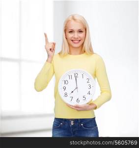 time, education and people concept - smiling young woman with wall clock showing 8 and finger up