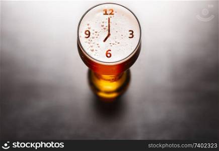 Time for beer concept. Clock or watch symbol on beer glass foam on black table, view from above. Time for beer concept