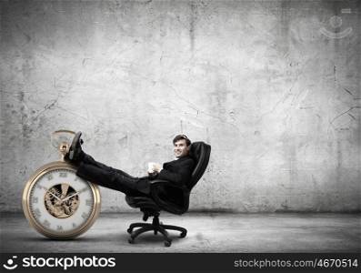 Time for break. Young handsome businessman sitting in chair with cup