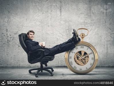 Time for break. Young handsome businessman sitting in chair with cup