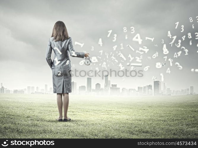 Time for business. Back view of businesswoman holding alarm clock against city background