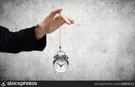 Time for business. Close up of male hand holding alarm clock on rope