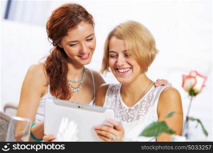 Time for coffee break!. Two young ladies in cafe using tablet pc