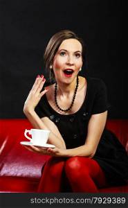 Time for coffee. Woman retro style. Elegant lady holding tea cup hot drink sitting on red sofa, indoor