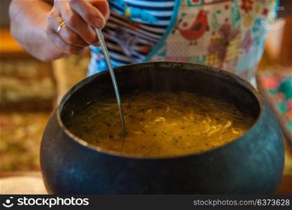 Time for dinner. Pouring soup from retro russian authenticity cast-iron dishes
