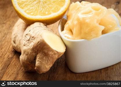 Time for make ginger tea. Fresh raw ginger rhizome root, honey and lemon on wooden rustic table.