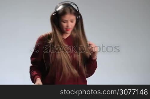 Time for music. Expressive cheerful brunette woman dancing to the music in headphones with fluttering amazing long hair. Excited hipster girl in big earphones going crazy of her music, dancing, gesturing, swinging her head along with to beat.