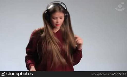 Time for music. Expressive cheerful brunette woman dancing to the music in headphones with fluttering amazing long hair. Excited hipster girl in big earphones going crazy of her music, dancing, gesturing, swinging her head along with to beat.