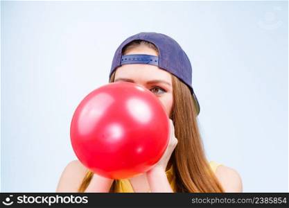 Time for party. Young trendy woman prepare birthday celebration decoration. Teenage girl in cap blowing red balloon.. Female teenager inflating red balloon.