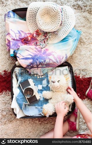 Time for summer vacation. Suitcase with packed summer clothes, a camera, a hat and sunglasses