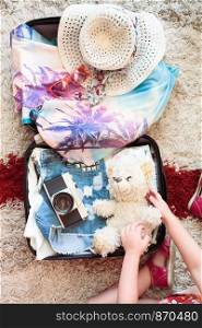 Time for summer vacation. Suitcase with packed summer clothes, a camera, a hat and sunglasses
