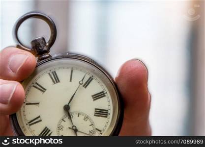 Time goes by: Man is holding a vintage watch in his hand, business context, copy space