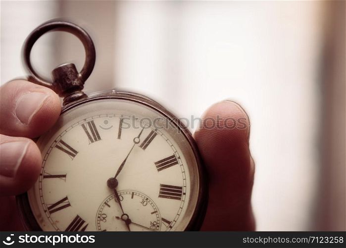 Time goes by: Man is holding a vintage watch in his hand, business context, copy space