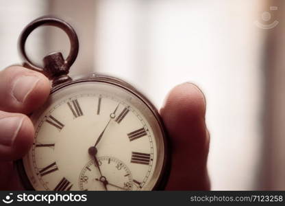 Time goes by: Man is holding a vintage watch in his hand, business context, copy space