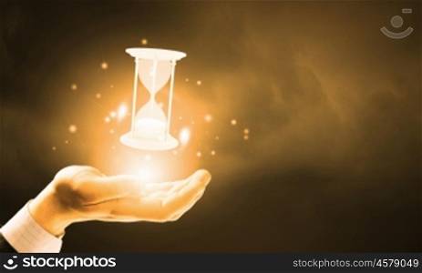 Time in hands. Close up of businessman holding sandglass in hand