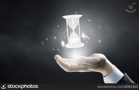 Time in hands. Close up of businessman holding sandglass in hand