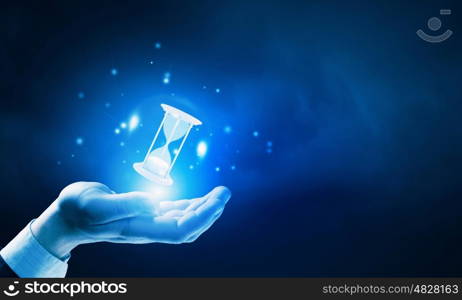 Time in hands. Close up of businessman holding sandglass in hand