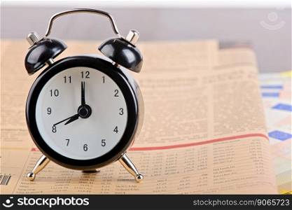 Time is money. Business concept. Alarm clock on the financial pink newspaper. Time is money. Business concept