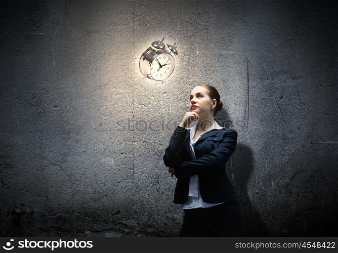Time is passing. Image of concentrated businesswoman looking at alarm clock