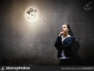Time is passing. Image of concentrated businesswoman looking at alarm clock