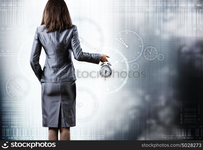 Time is passing. Rear view of businesswoman holding old alarm clock