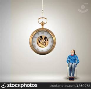 Time is passing. Young woman in casual looking at pocket clock