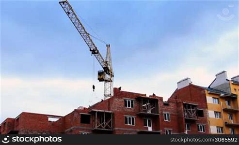 time-lapse construction activity, tower crane gives two concrete slabs, some workers install them, while others lay bricks
