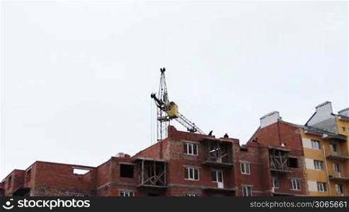 time-lapse construction activity, workers lay bricks, tower crane gives concrete slab, wideangle