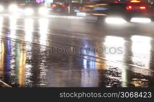 Time lapse of city traffic at night: cars with bright headlights moving on wet road.