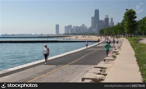 Time lapse of cyclists and runners enjoying a summer day on the Lakefront path along the Lake Michigan shoreline in Chicago.