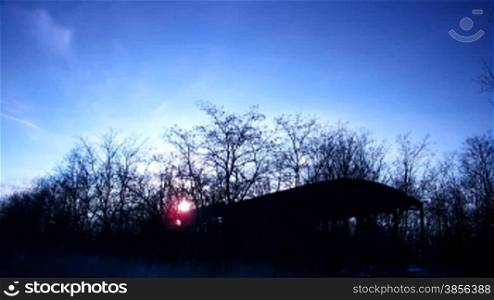 time lapse of running clouds on sunset among trees.