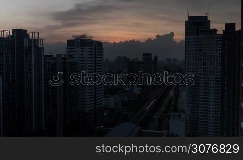 Time lapse shot of cityscape with skyscrapers and buildings on the foreground and industrial smog under city on the background in the evening. Bangkok, Thailand