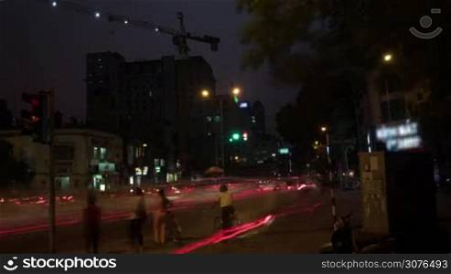Time lapse shot of intersection at night, people and bikes on the pedestrian cross walking, Hanoi, Vietnam.