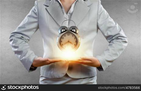 Time management. Close up of businesswoman holding in hands alarm clock