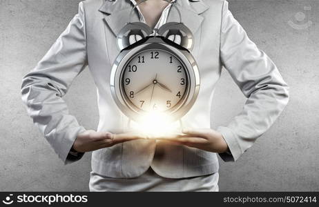 Time management. Close up of businesswoman holding in hands alarm clock