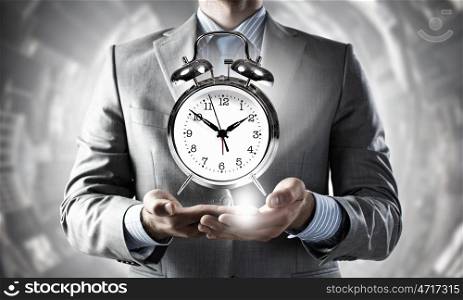 Time management. Close up of man holding alarm clock in hands