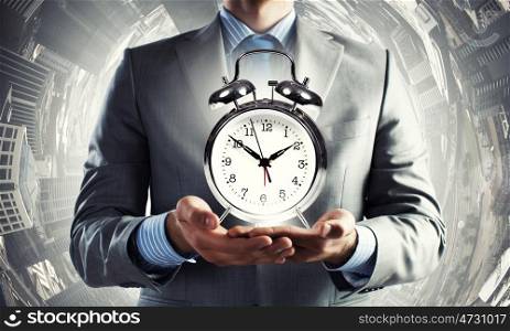 Time management. Close up of man holding alarm clock in the hands