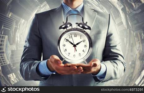 Time management. Close up of man holding alarm clock in the hands