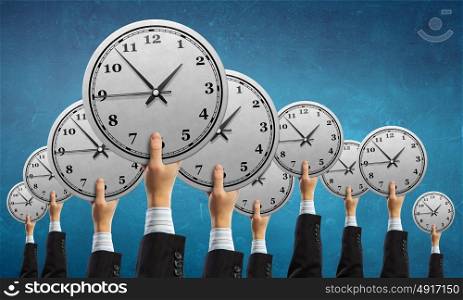 Time management concept. Many hands of business people holding alarm clock