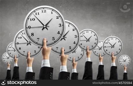 Time management. Many hands of business people holding alarm clock