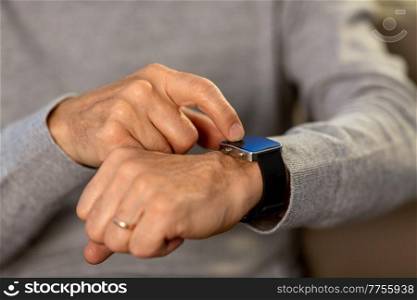 time, morning and people concept - close up of senior man hands with wristwatch or smartwatch at home. close up of senior man hands with smartwatch