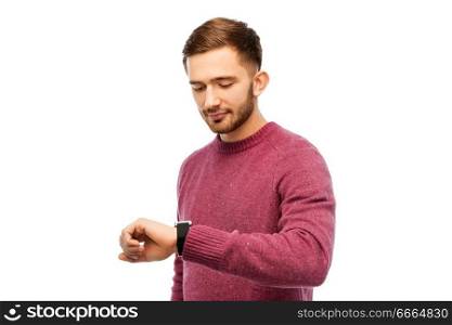 time, punctuality and people concept - smiling young man looking at wristwatch over white background. smiling young man checking time on wristwatch