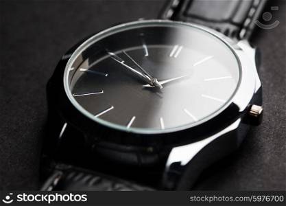 time, punctuality, object and accessory concept - close up of black classic male wristwatch