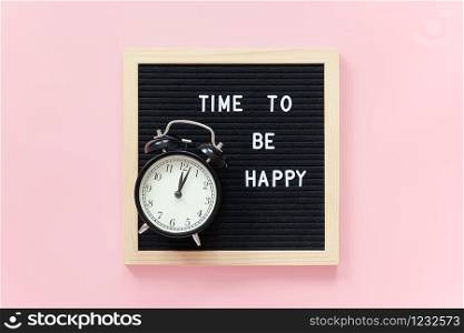 Time to be happy. Motivational quote on letterboard and black alarm clock on pink background. Top view Flat lay Concept inspirational quote of the day.. Time to be happy. Motivational quote on letterboard and black alarm clock on pink background. Top view Flat lay Concept inspirational quote of the day