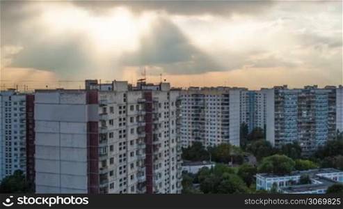 Timelapse and panning shot of sky during sunset with dark heavy clouds gathering in the sky over block of multistorey houses in the city