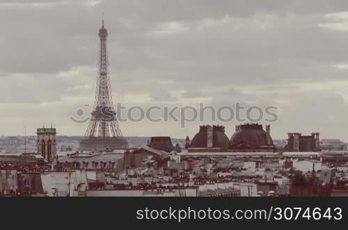 Timelapse of clouds sailing over Paris, view to the city and Eiffel Tower with working elevators. Retro color toned shot with the capital symbol