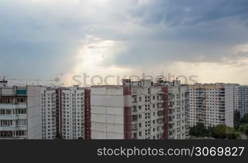 Timelapse of evening sky over the block of houses in the city with dark clouds gathering