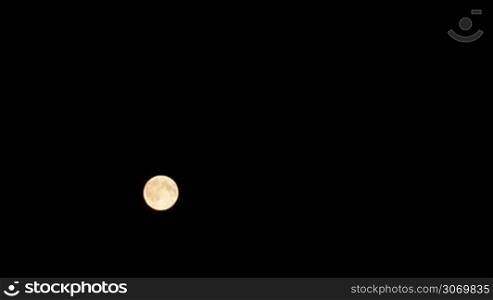 Timelapse of full moon moving against black night sky