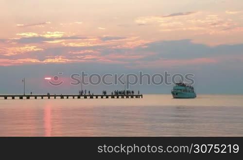 Timelapse of people boarding the boat from sea pier at sunset