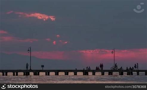 Timelapse of people walking on the pier in the sea during the evening and in the dusk